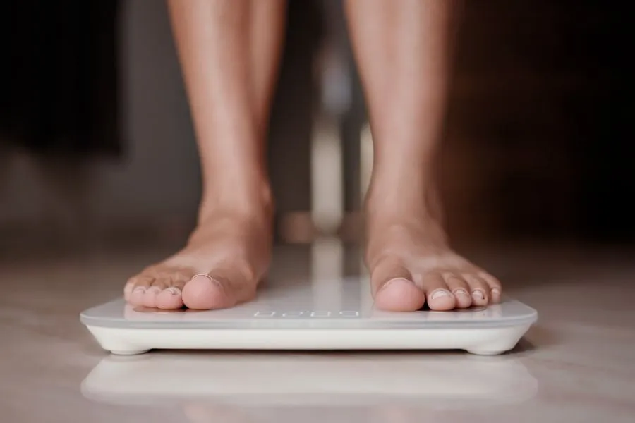 woman weighing herself on scale to check weight loss